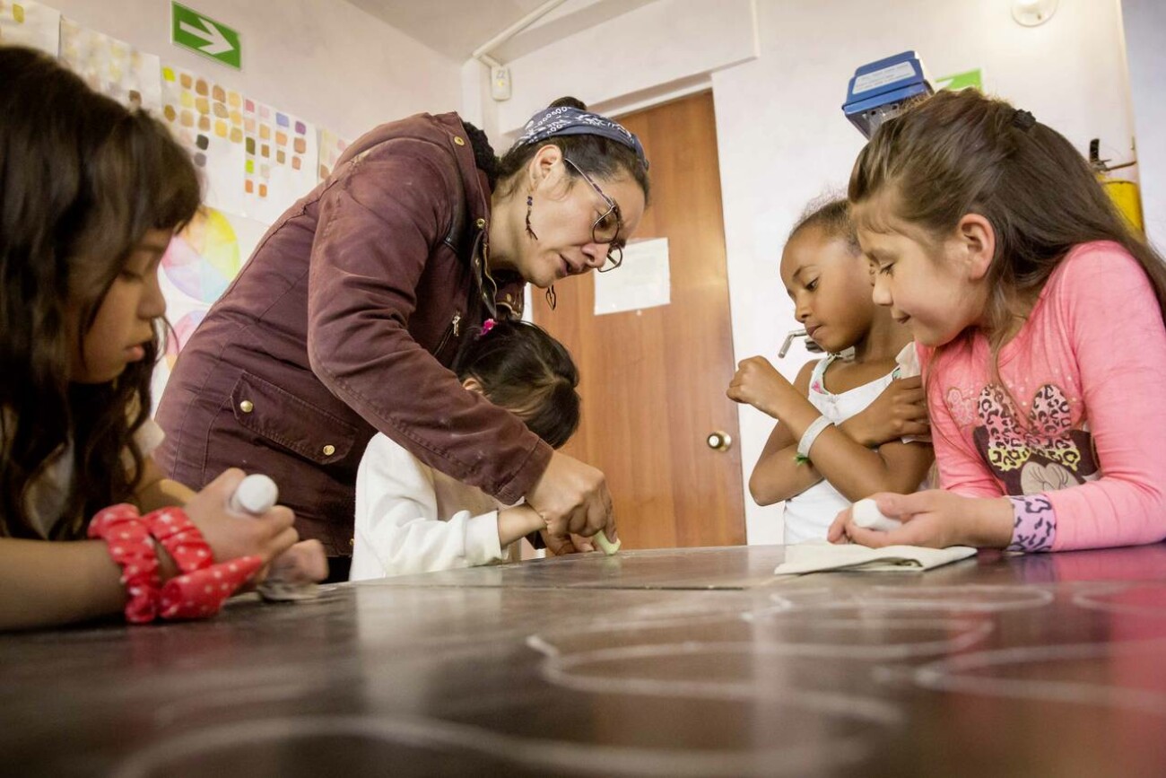 Die Lehrerin hilft Kindern beim Malen mit Kreide