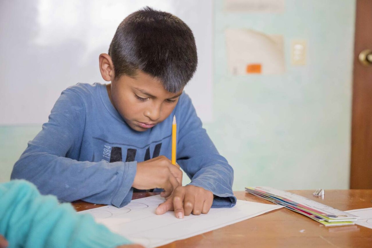 Ein Junge malt auf einem Blatt Papier