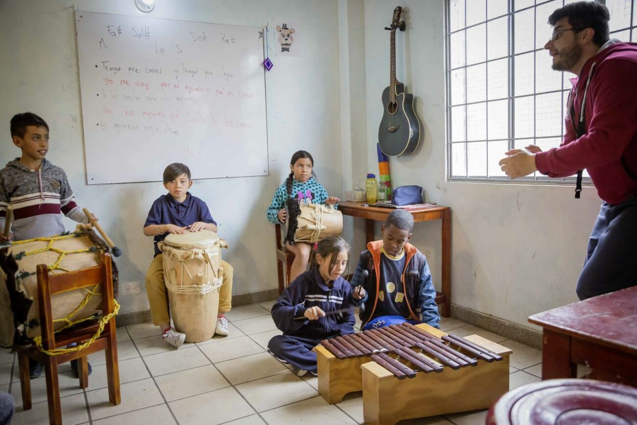 Kinder und ein Lehrer spielen Trommeln und Xylophon