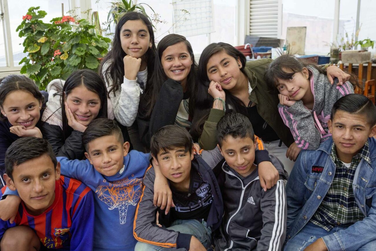 11 Jugendliche sitzen beieinander und schauen in die Kamera